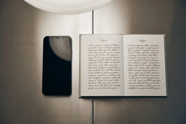 Mesa vista de cima com celular e caderno aberto lado a lado, representando duas camadas distintas de automação