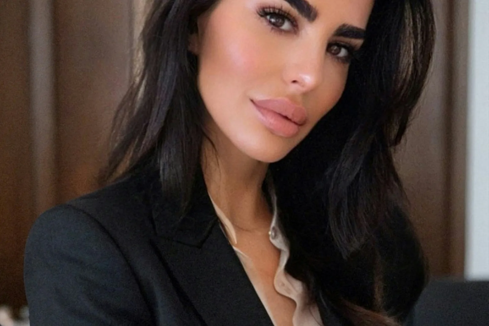 Mulher profissional com blazer preto e camisa clara olha para a câmera, transmitindo confiança e excelência em gestão de clínicas de saúde.