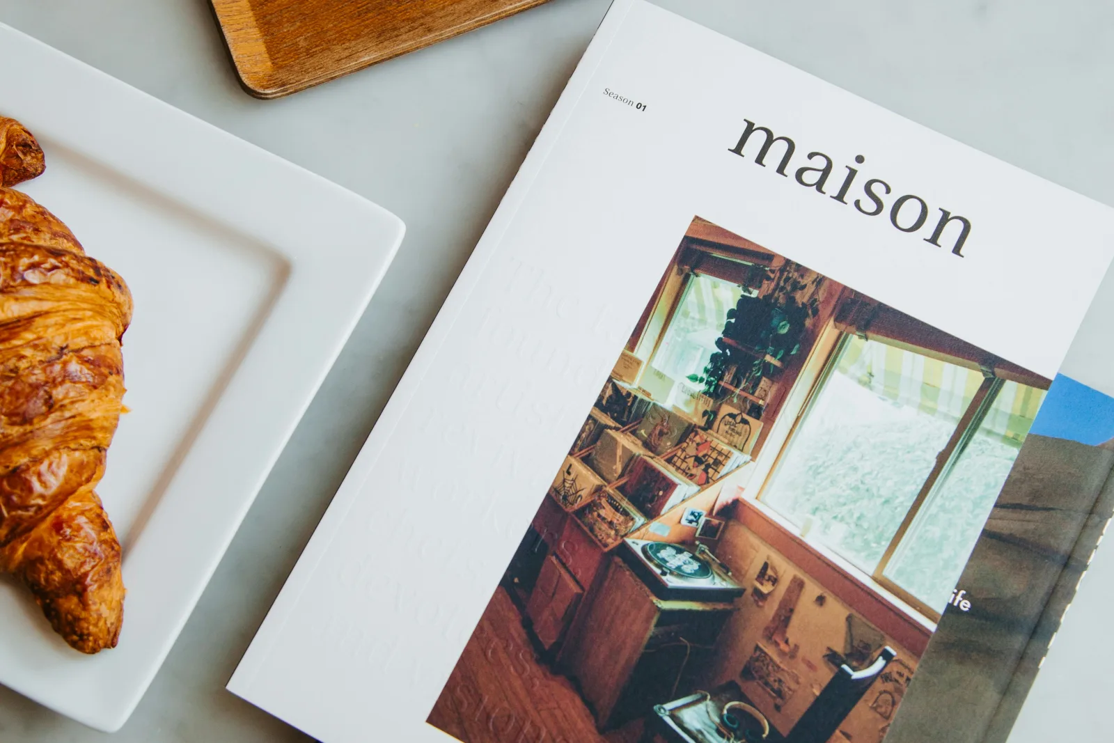 Mesa de mármore com xícara de café, copo de água, croissant e revista em sala de espera de clínica. Ilustra a importância de conduzir a conversa do paciente.