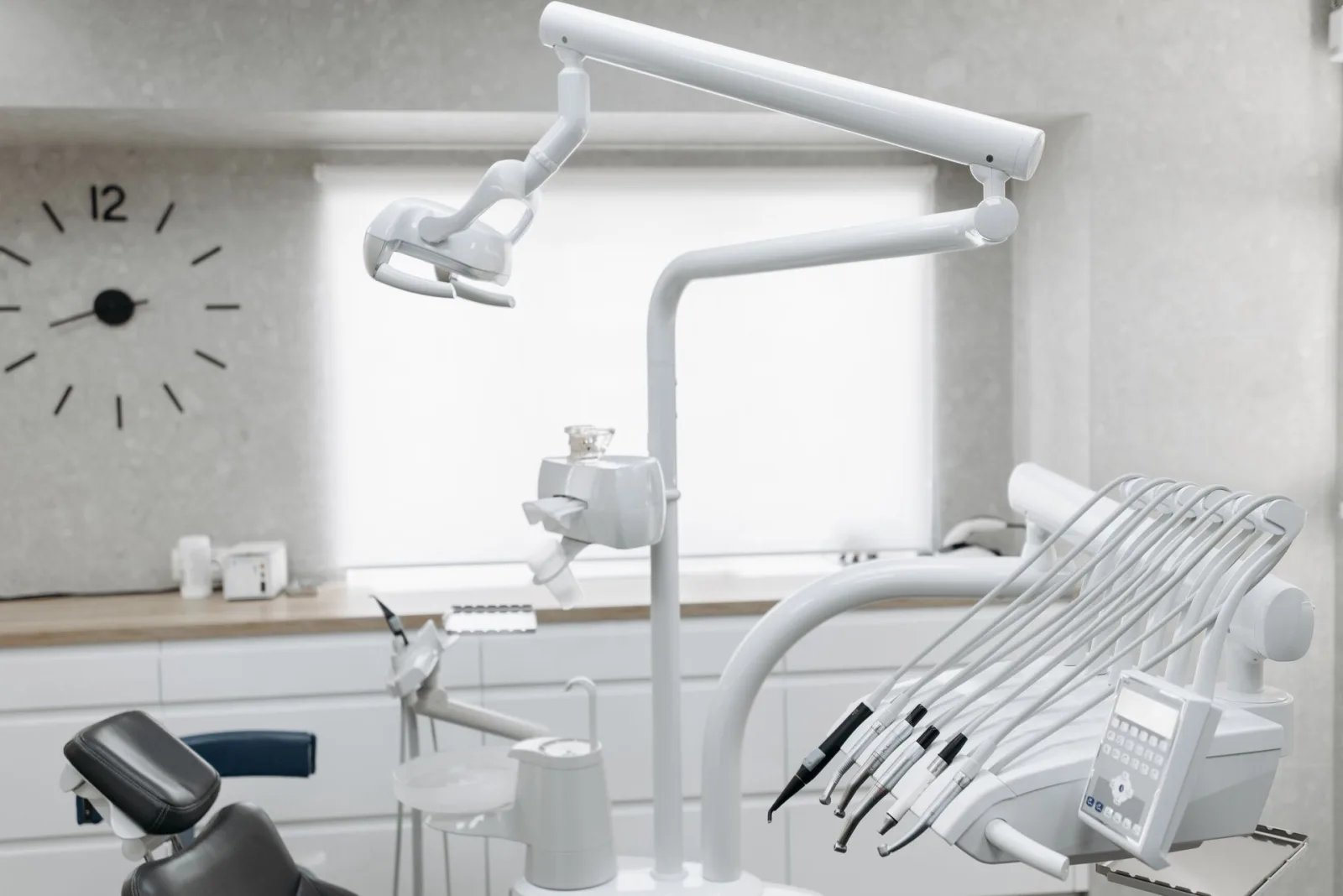Consultório odontológico moderno e impecavelmente limpo, com cadeira de dentista, equipamentos e janela. Ambiente profissional de clínica de saúde.
