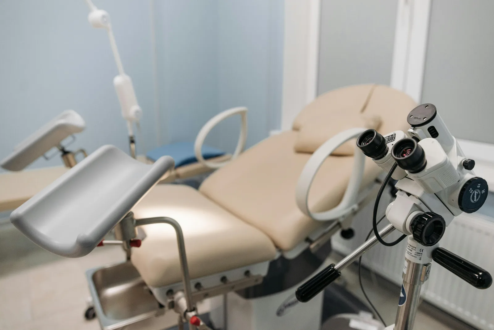 Sala de exame médico em clínica particular, com cadeira ginecológica e colposcópio. Essencial para entender a auditoria de glosas.