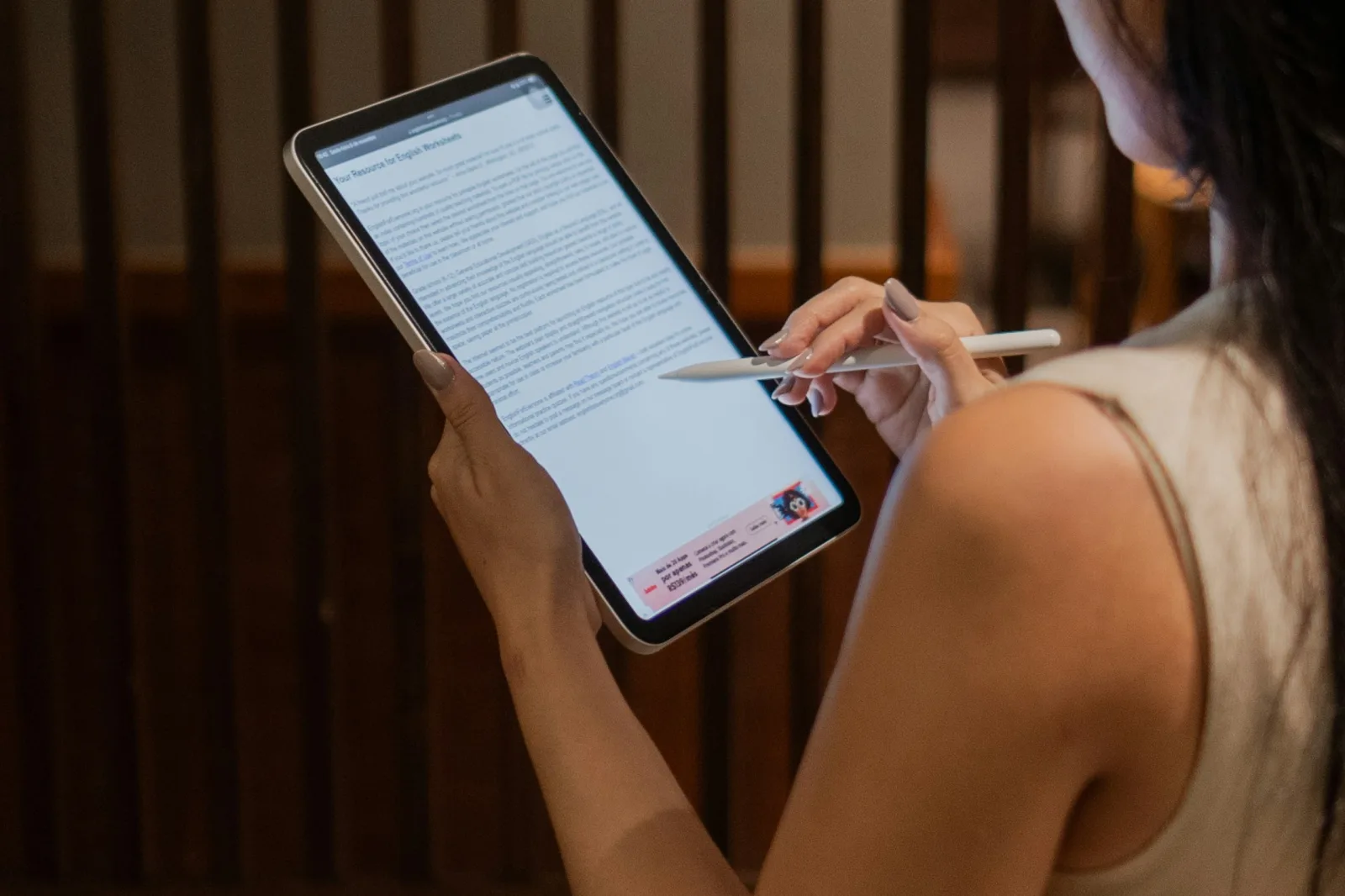 Profissional de saúde, de perfil, utiliza um tablet com caneta digital em um ambiente de consultório moderno e bem iluminado, simbolizando a gestão eficiente da agenda e comunicação com pacientes.