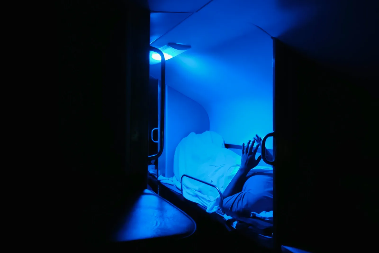 Silhueta de pessoa em ambiente escuro, banhada por luz azul intensa, representando a inovação e o cuidado tecnológico em clínicas.