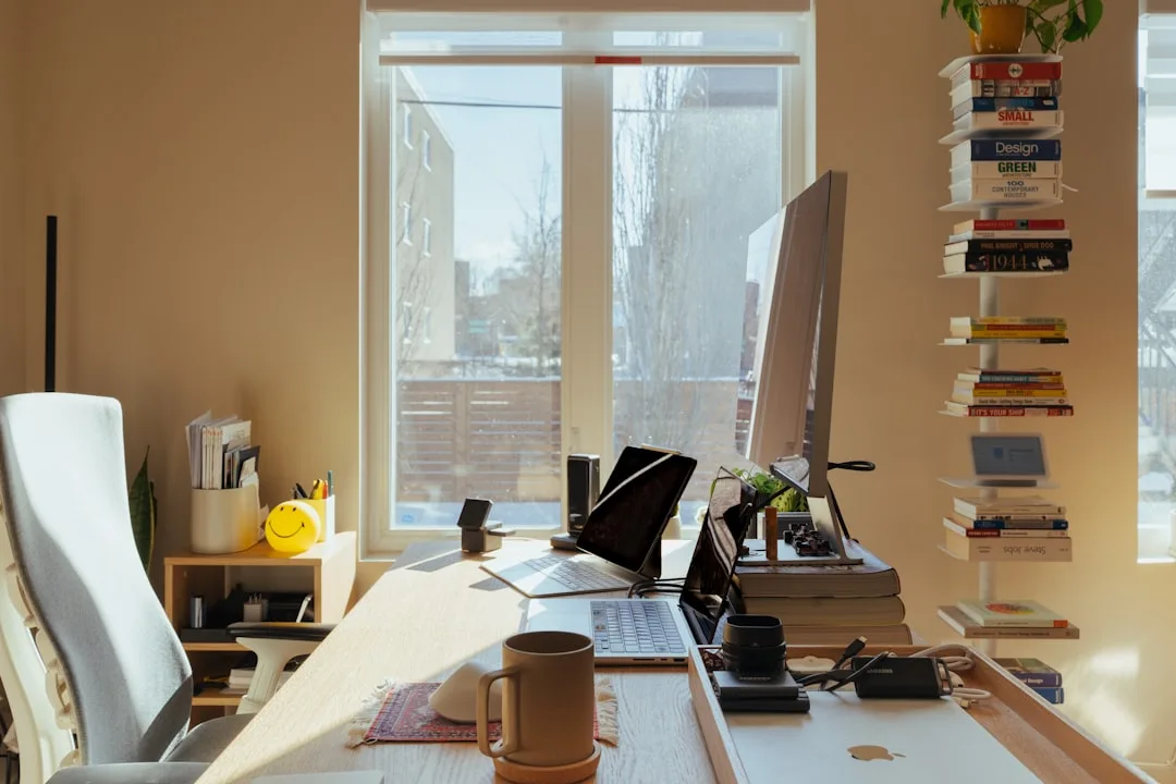 Mesa de escritório organizada com monitor e laptop em home office iluminado pelo sol, ideal para análise de dados e otimização de IA.