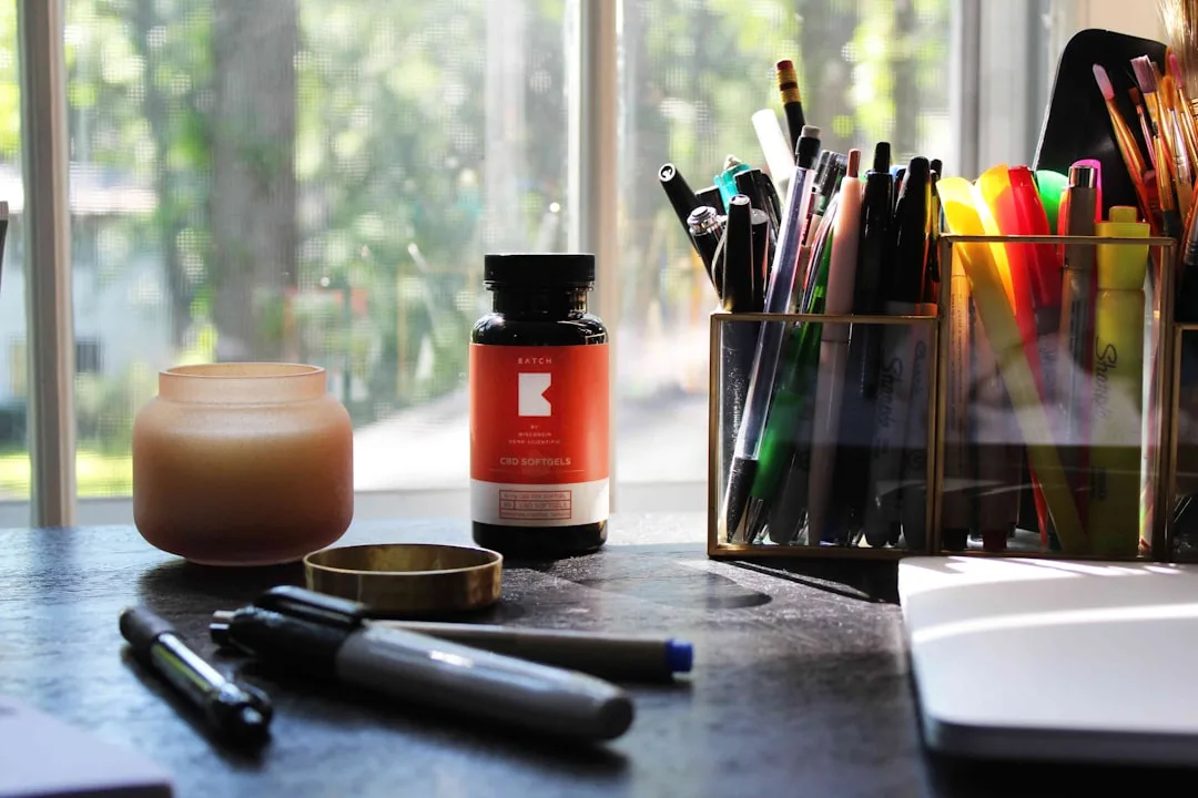 Mesa de trabalho organizada com itens de escritório, caderno e caneta, iluminada por luz natural, simbolizando foco e decisão estratégica em gestão de clínicas.