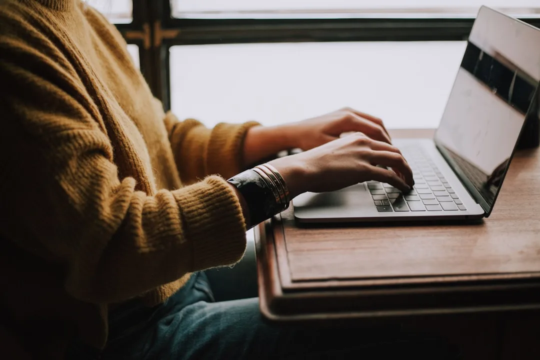 Pessoa concentrada digitando em laptop prateado, simbolizando a verificação e alinhamento de expectativas antes de agendamentos em clínicas de saúde.