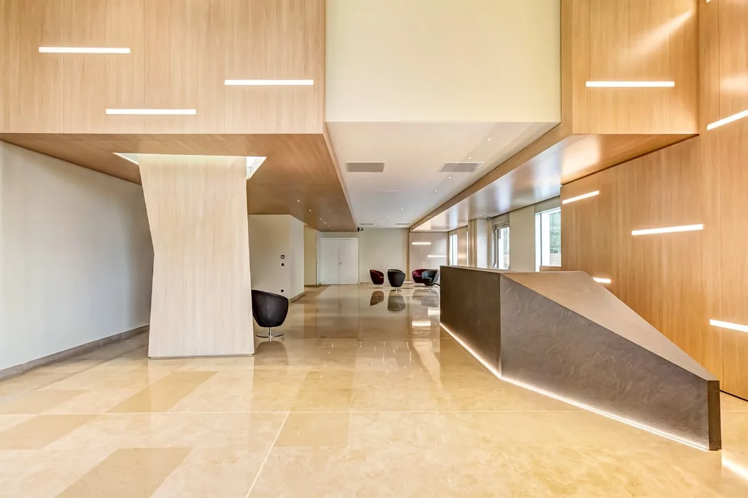 Hall de entrada moderno e elegante de clínica, com painéis de madeira e balcão iluminado, refletindo organização e cuidado ao paciente.