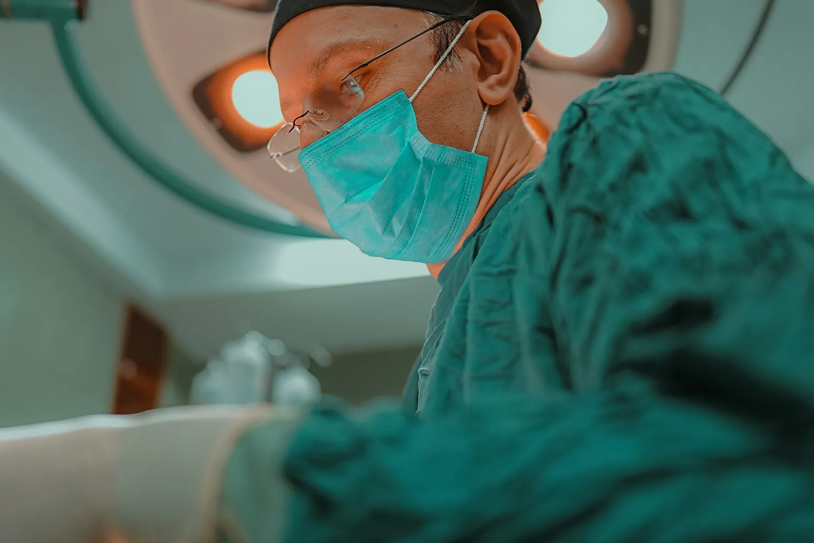 Cirurgião com máscara e luvas realiza procedimento sob foco cirúrgico, simbolizando precisão e cuidado em ambiente hospitalar.